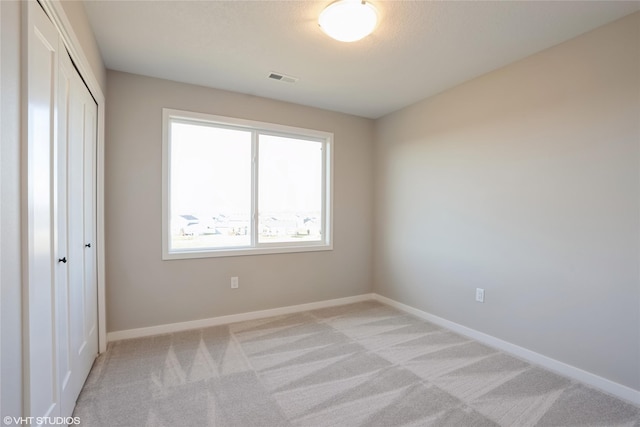 unfurnished bedroom with light carpet and a closet