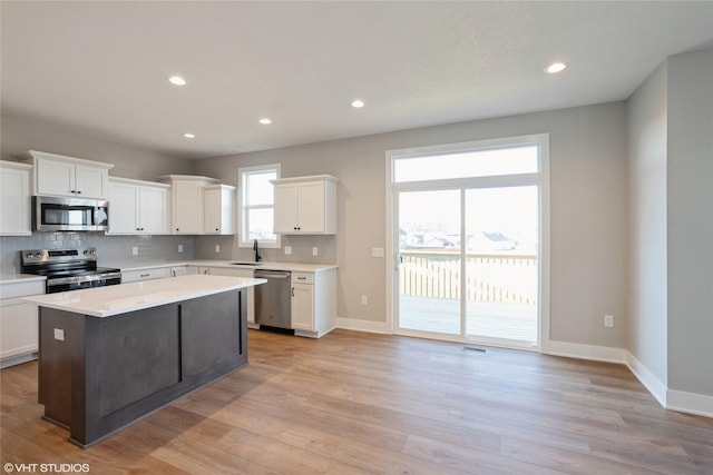 kitchen featuring a center island, white cabinets, sink, appliances with stainless steel finishes, and light hardwood / wood-style floors