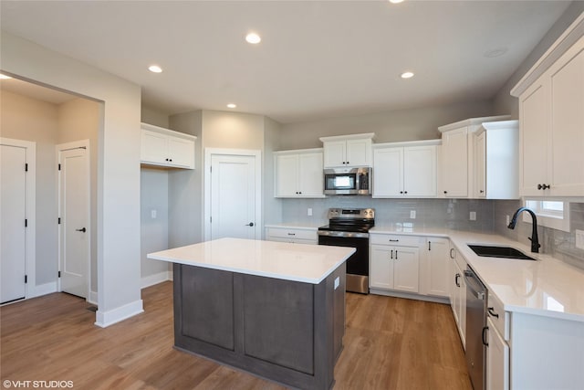 kitchen featuring white cabinets, sink, a kitchen island, and appliances with stainless steel finishes