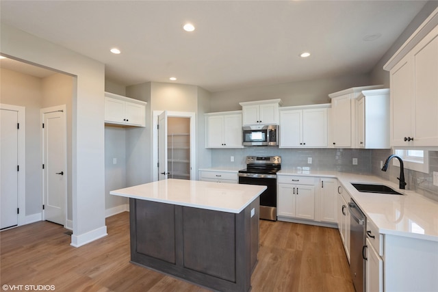 kitchen with white cabinets, a center island, sink, and stainless steel appliances