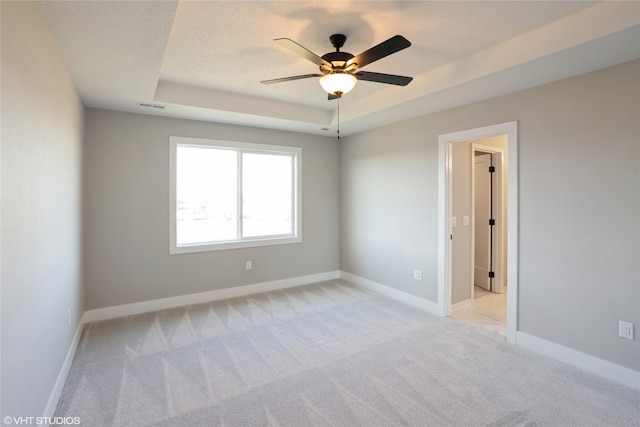 carpeted empty room with a tray ceiling and ceiling fan