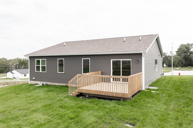 rear view of house featuring a shingled roof, a deck, and a yard