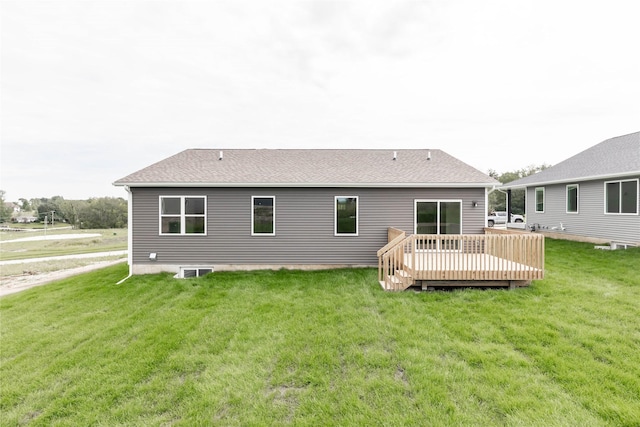 back of house featuring a deck, roof with shingles, and a lawn