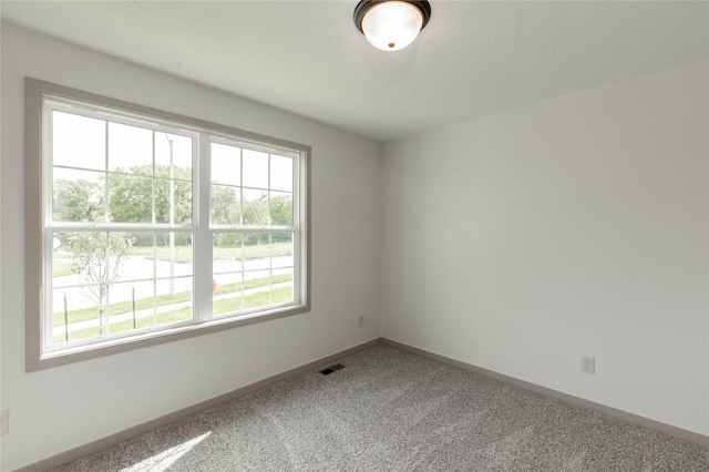 spare room featuring carpet, visible vents, and baseboards