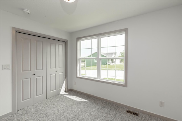 unfurnished bedroom with a closet, carpet, visible vents, and baseboards