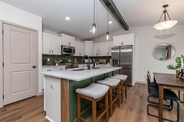 kitchen with lofted ceiling with beams, appliances with stainless steel finishes, a sink, and tasteful backsplash