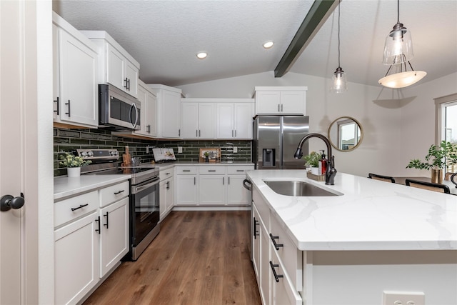 kitchen featuring tasteful backsplash, a center island with sink, vaulted ceiling with beams, stainless steel appliances, and a sink