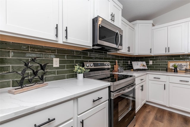 kitchen with tasteful backsplash, white cabinets, dark wood-style flooring, light stone countertops, and stainless steel appliances