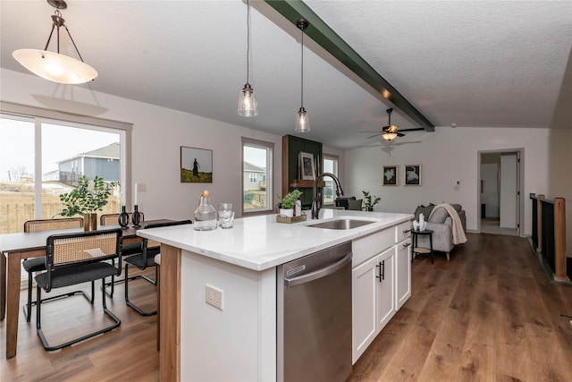 kitchen featuring vaulted ceiling with beams, wood finished floors, a sink, white cabinets, and stainless steel dishwasher