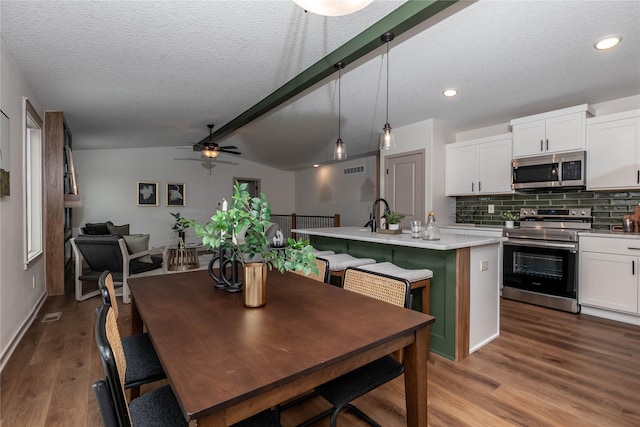 dining space featuring a ceiling fan, lofted ceiling with beams, wood finished floors, a textured ceiling, and recessed lighting