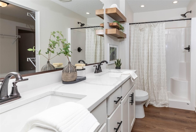 bathroom with curtained shower, a sink, toilet, and wood finished floors