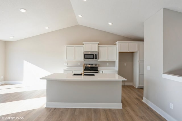 kitchen featuring appliances with stainless steel finishes, a center island with sink, white cabinetry, and light hardwood / wood-style flooring