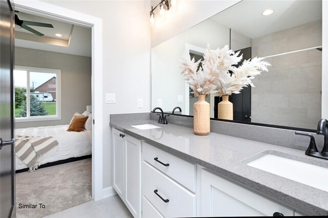 bathroom featuring vanity, ceiling fan, and a tray ceiling