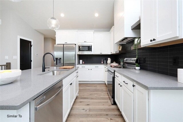 kitchen featuring backsplash, stainless steel appliances, light hardwood / wood-style floors, and pendant lighting