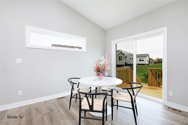 dining space with light wood-type flooring and vaulted ceiling