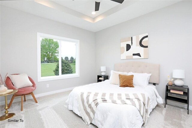 bedroom with light colored carpet, ceiling fan, and a raised ceiling