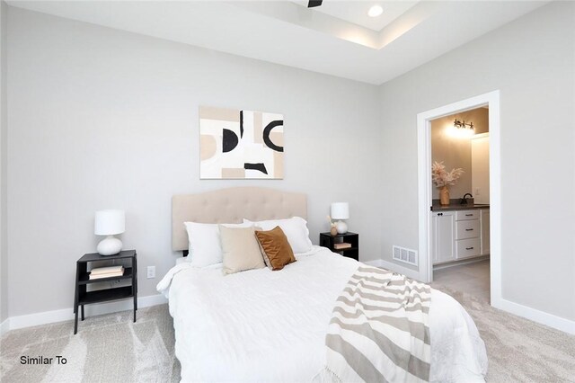 bedroom featuring ensuite bath and light colored carpet