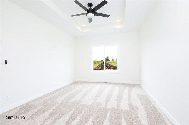 unfurnished room with light carpet, a raised ceiling, and ceiling fan