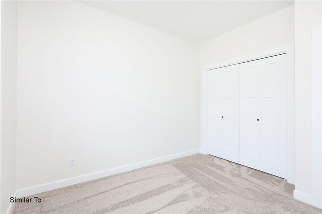 unfurnished bedroom with light colored carpet and a closet