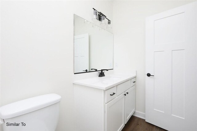 bathroom with vanity, toilet, and hardwood / wood-style flooring