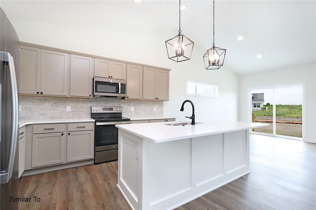 kitchen with backsplash, stainless steel appliances, dark hardwood / wood-style flooring, sink, and a kitchen island with sink