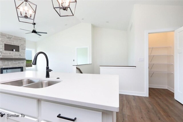 kitchen featuring hardwood / wood-style floors, ceiling fan with notable chandelier, sink, hanging light fixtures, and vaulted ceiling