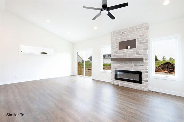 unfurnished living room featuring wood-type flooring, ceiling fan, vaulted ceiling, and a stone fireplace