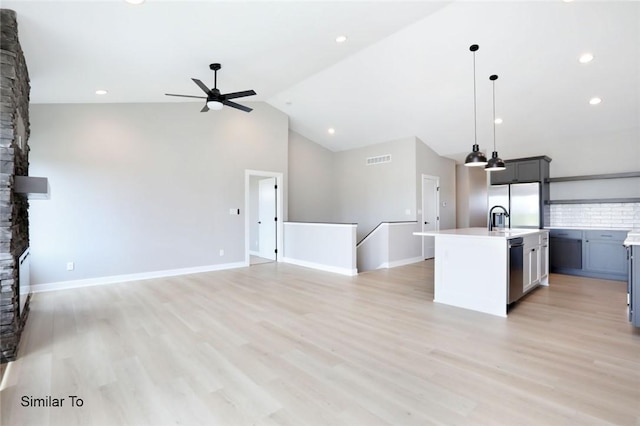 2412 NE 6th St, Grimes, IA 50111 - unfurnished living room featuring a stone fireplace, a ceiling fan, visible vents, high vaulted ceiling, and light wood finished floors