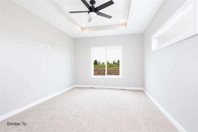 unfurnished room with a raised ceiling, a ceiling fan, recessed lighting, baseboards, and light colored carpet