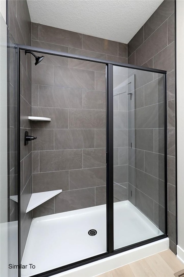 bathroom with a stall shower and a textured ceiling