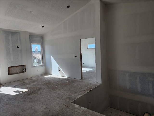 unfurnished living room featuring lofted ceiling and a textured ceiling