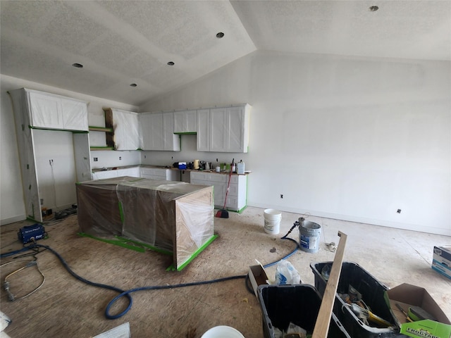 2412 NE 6th St, Grimes, IA 50111 - kitchen with a center island, white cabinetry, vaulted ceiling, and a textured ceiling