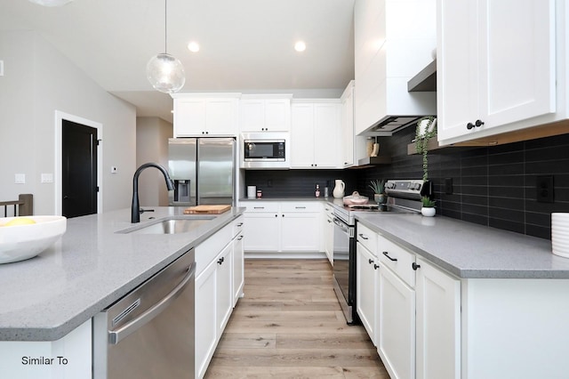 kitchen with backsplash, light wood-style flooring, appliances with stainless steel finishes, white cabinetry, and a sink