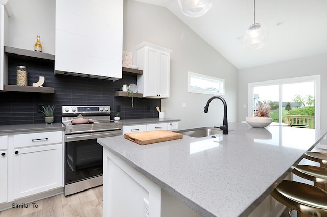 kitchen with a center island with sink, open shelves, a sink, a kitchen breakfast bar, and stainless steel electric range oven