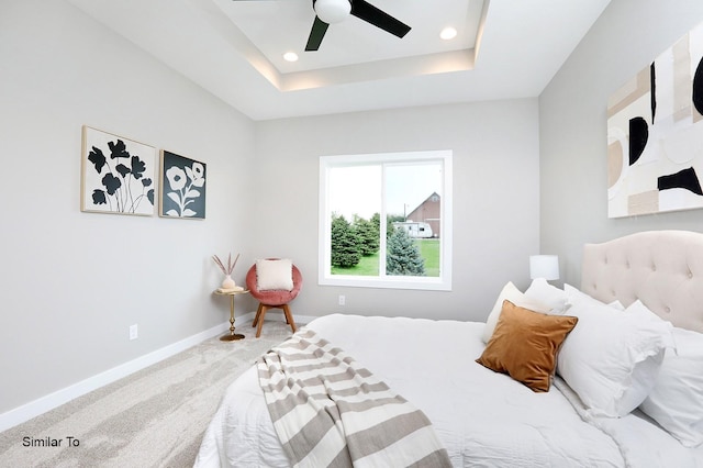 carpeted bedroom with a ceiling fan, a tray ceiling, recessed lighting, and baseboards