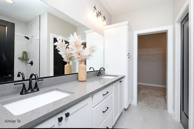 bathroom with a spacious closet, double vanity, walk in shower, and a sink