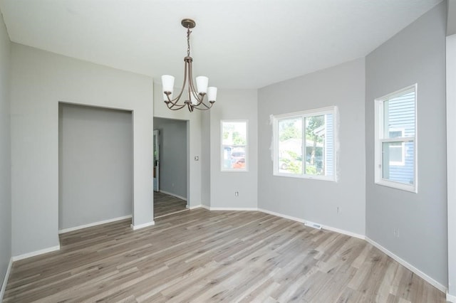 1125 Clinton Ave, Des Moines, IA 50313 - empty room featuring a chandelier, light wood-style floors, and baseboards