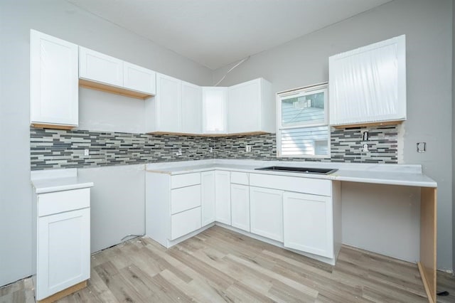 1125 Clinton Ave, Des Moines, IA 50313 - kitchen featuring light wood-type flooring, tasteful backsplash, white cabinetry, and light countertops