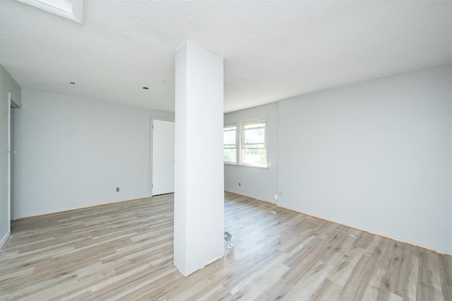 1125 Clinton Ave, Des Moines, IA 50313 - empty room with wood finished floors, a textured ceiling, and baseboards