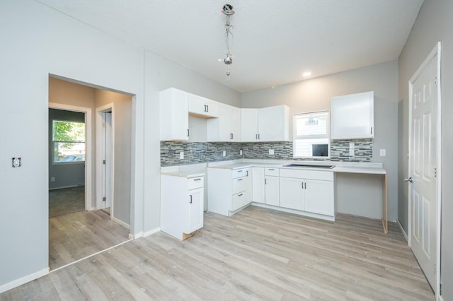 1125 Clinton Ave, Des Moines, IA 50313 - kitchen featuring light wood finished floors, decorative backsplash, white cabinets, light countertops, and recessed lighting