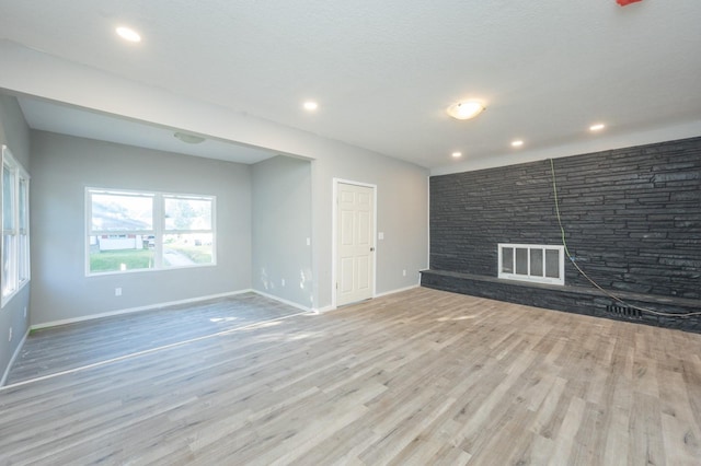 1125 Clinton Ave, Des Moines, IA 50313 - unfurnished living room featuring wood finished floors, baseboards, recessed lighting, and a fireplace