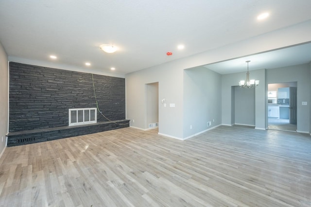 1125 Clinton Ave, Des Moines, IA 50313 - unfurnished living room featuring a fireplace, a chandelier, light wood-type flooring, baseboards, and recessed lighting