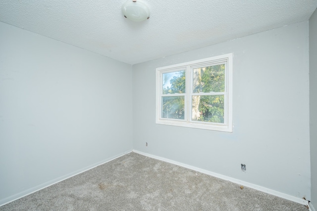 carpeted empty room featuring a textured ceiling