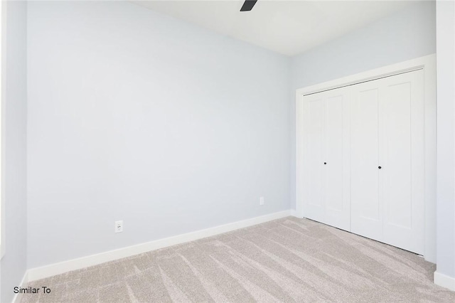 unfurnished bedroom featuring a closet, baseboards, carpet, and a ceiling fan