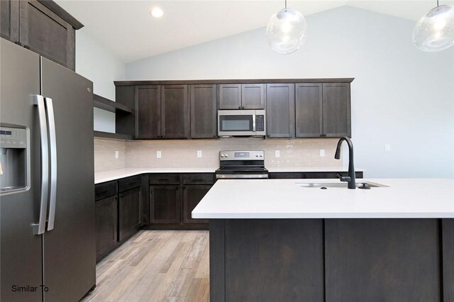 kitchen with vaulted ceiling, light hardwood / wood-style flooring, appliances with stainless steel finishes, sink, and decorative backsplash