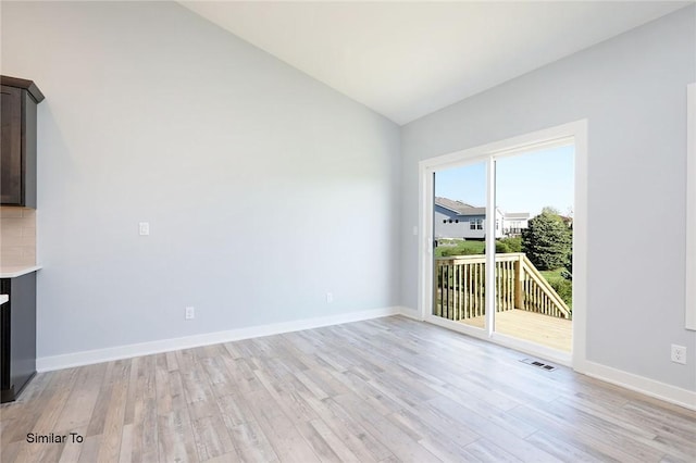 unfurnished living room featuring light wood finished floors, visible vents, baseboards, and vaulted ceiling