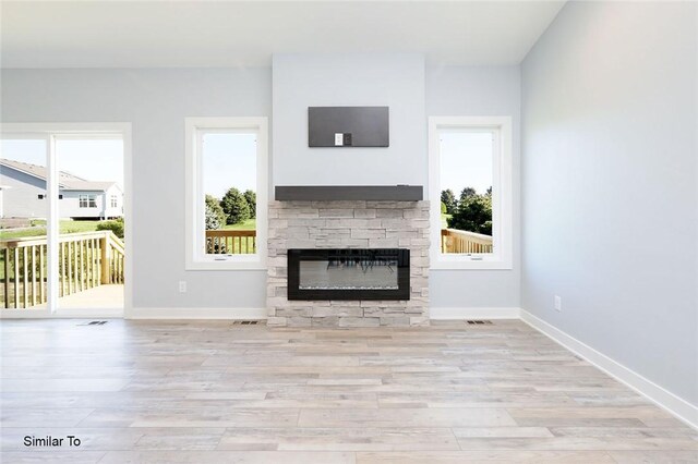 unfurnished living room featuring visible vents, baseboards, wood finished floors, and a fireplace