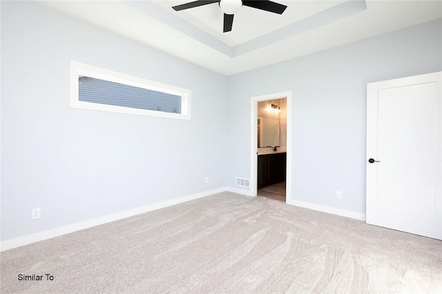 unfurnished bedroom featuring visible vents, ensuite bathroom, baseboards, carpet flooring, and a raised ceiling