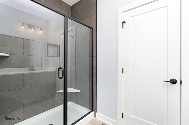 bathroom featuring a shower stall and baseboards