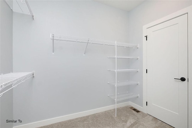 walk in closet with visible vents and light colored carpet